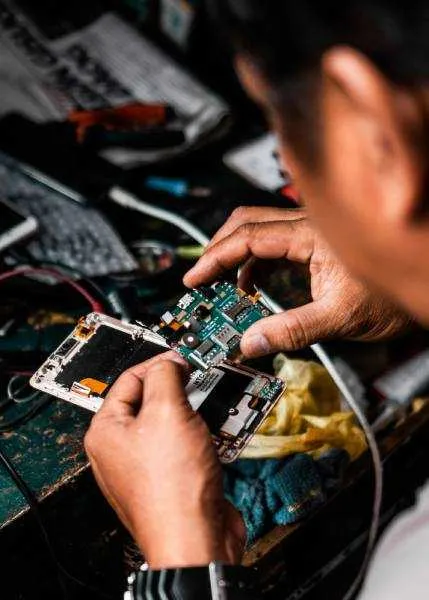 A technician using fine tools to repair a circuit board at a workbench